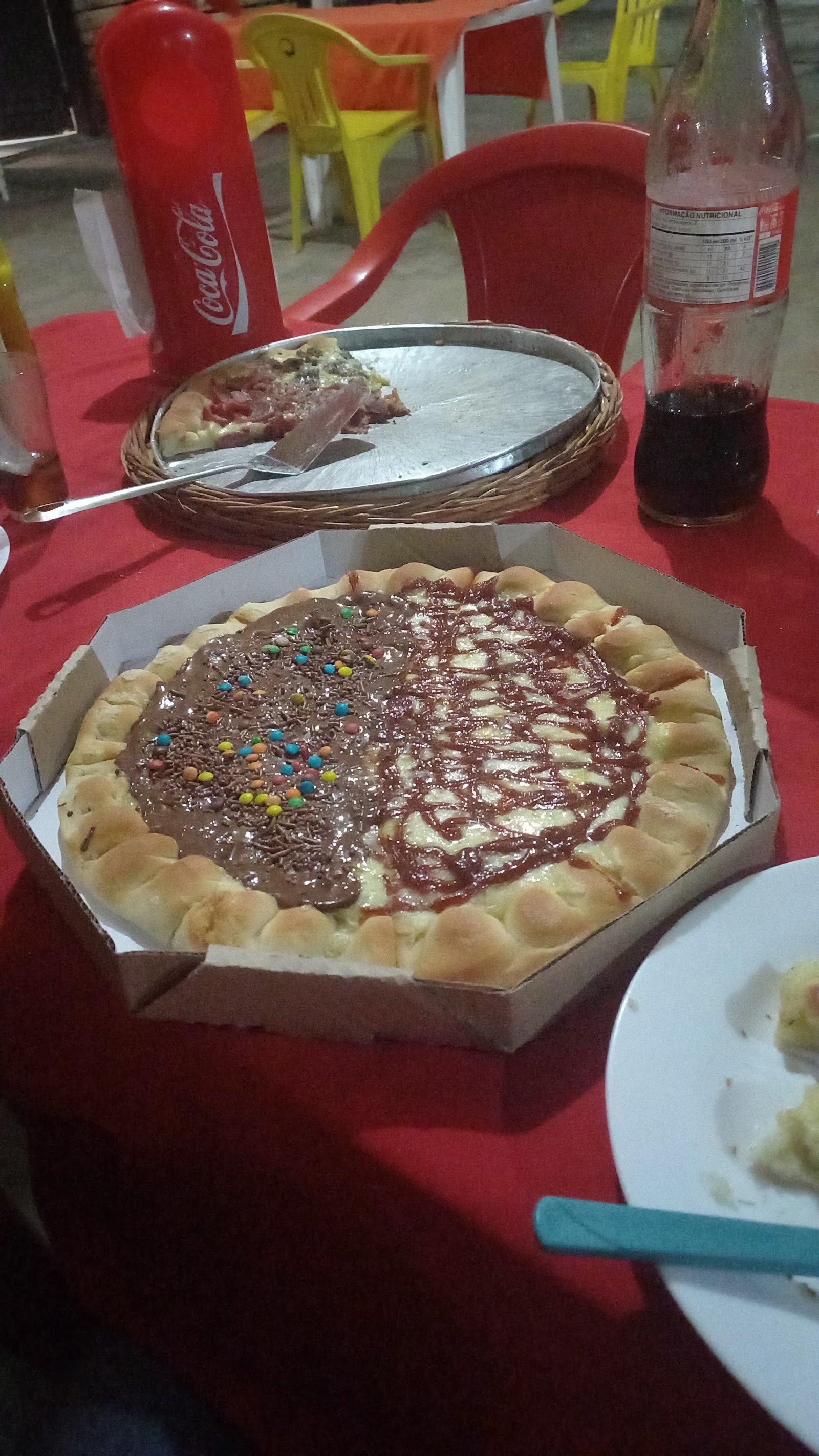 Pizza doce de brigadeiro na mesa da pizzaria ao lado de refrigerante